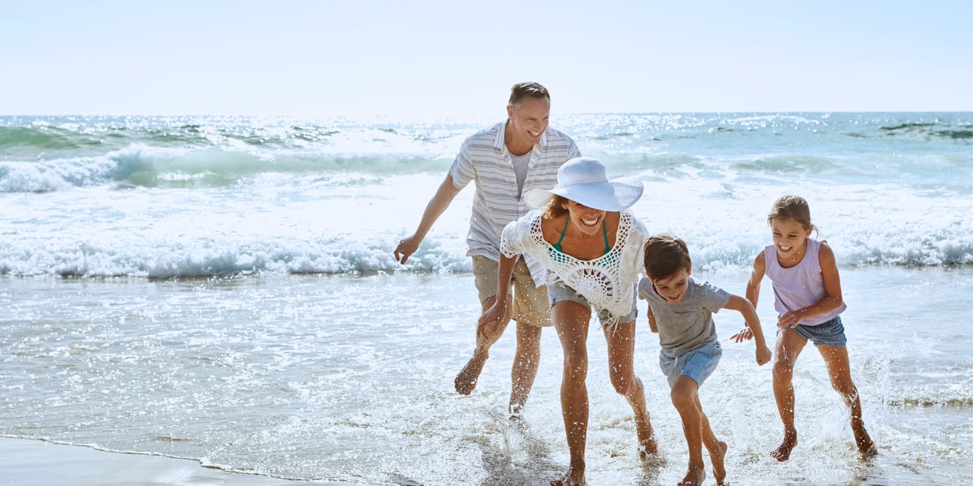 Family running into the waves
